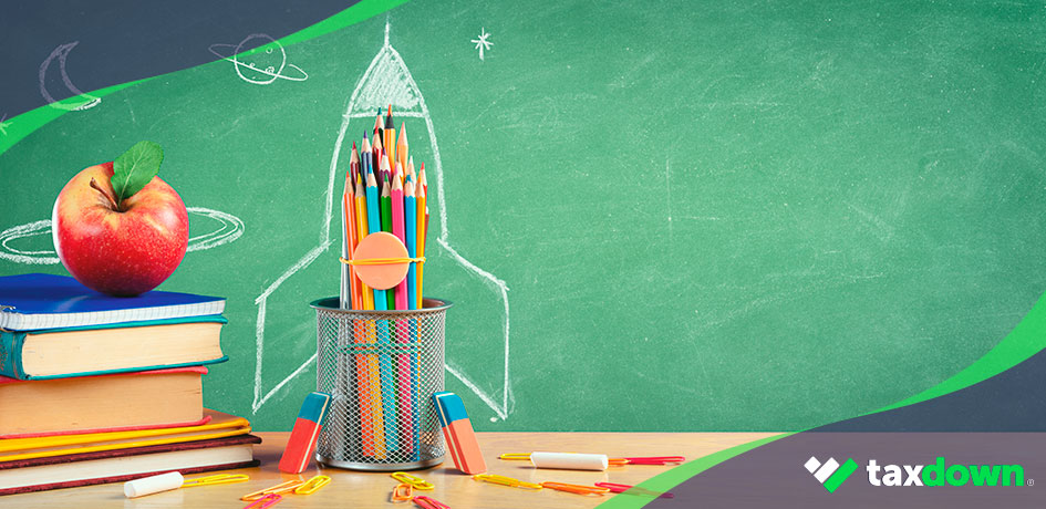 Gastos educativos deducibles en la renta pizarra con un cohete pintado con tiza, libros y un cubilete con lapices